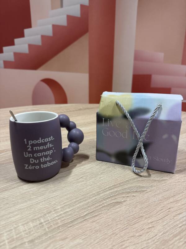 Tasse violette Chloé & Anouck by Femini.tea avec anse perlée design et cuillère, sur fond graphique rose.